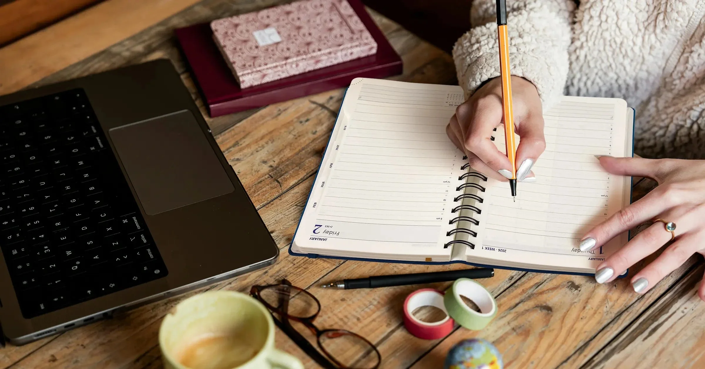 Person planning daily habits with notebook and calendar